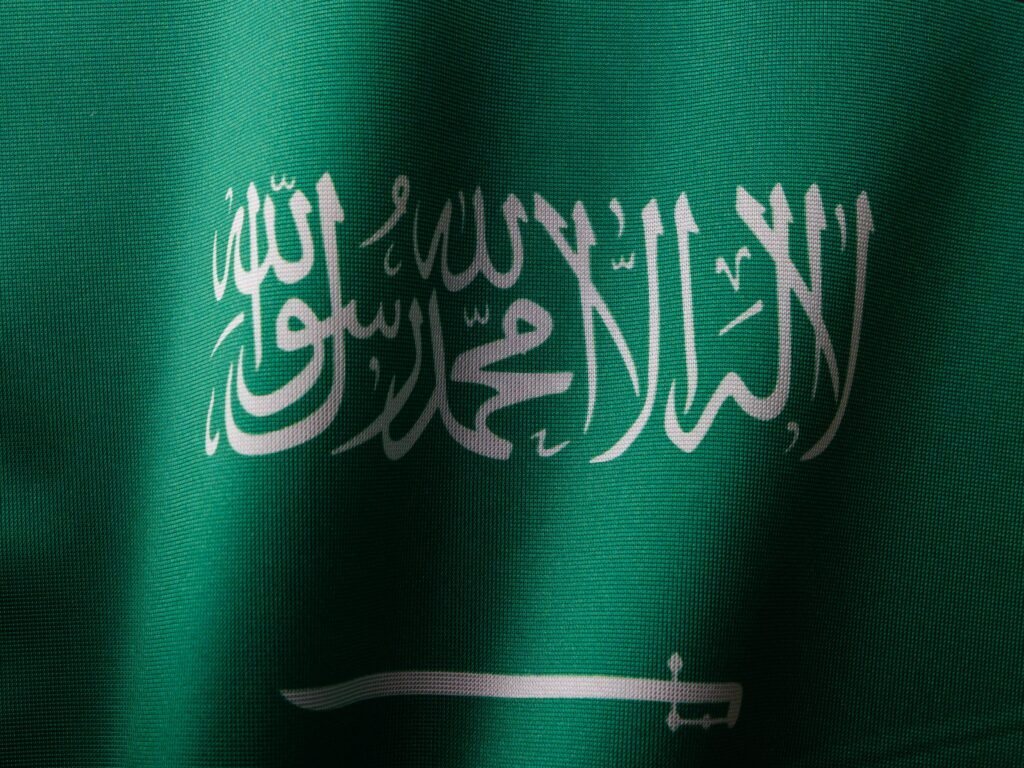 pexels-photo-15483696-15483696 Detailed close-up of the Saudi Arabian flag showcasing the elegant Arabic script and vibrant green color.